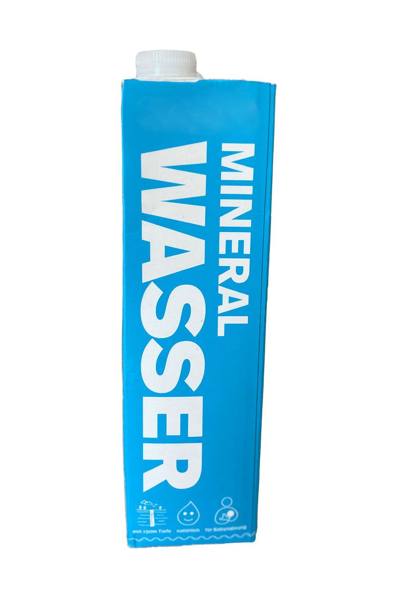 Blaue Kartonverpackung mit weißem "MINERAL WASSER"-Schriftzug. Oben weißer Verschluss, unten Piktogramme.