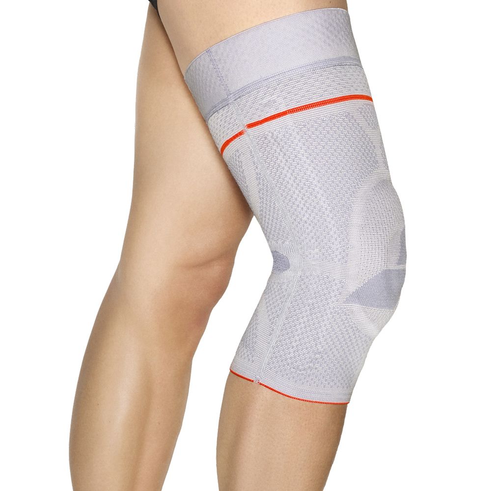 Graue Kniebandage mit rotem Rand, getragen am Bein einer Person. Zeigt die Passform.