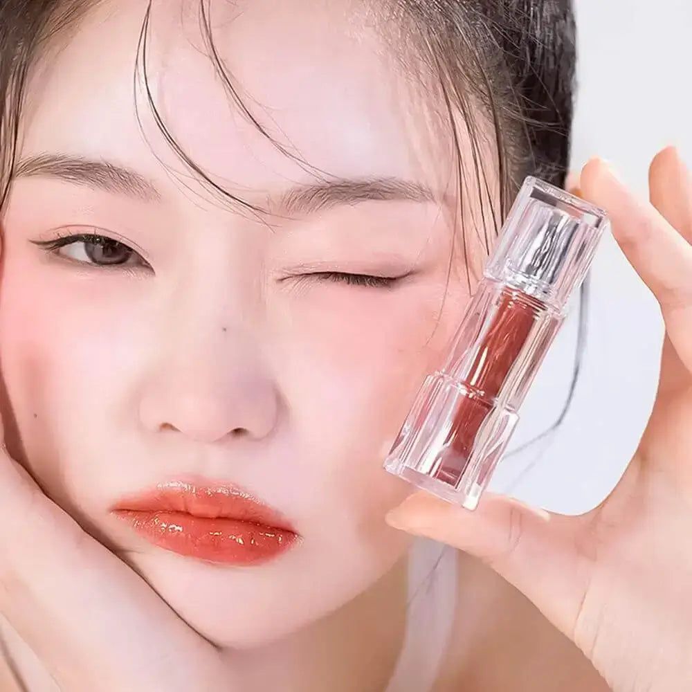 Frau mit Lippenstift in der Hand. Lippenstift in transparentem Behälter. Frau mit geschminkten Lippen.