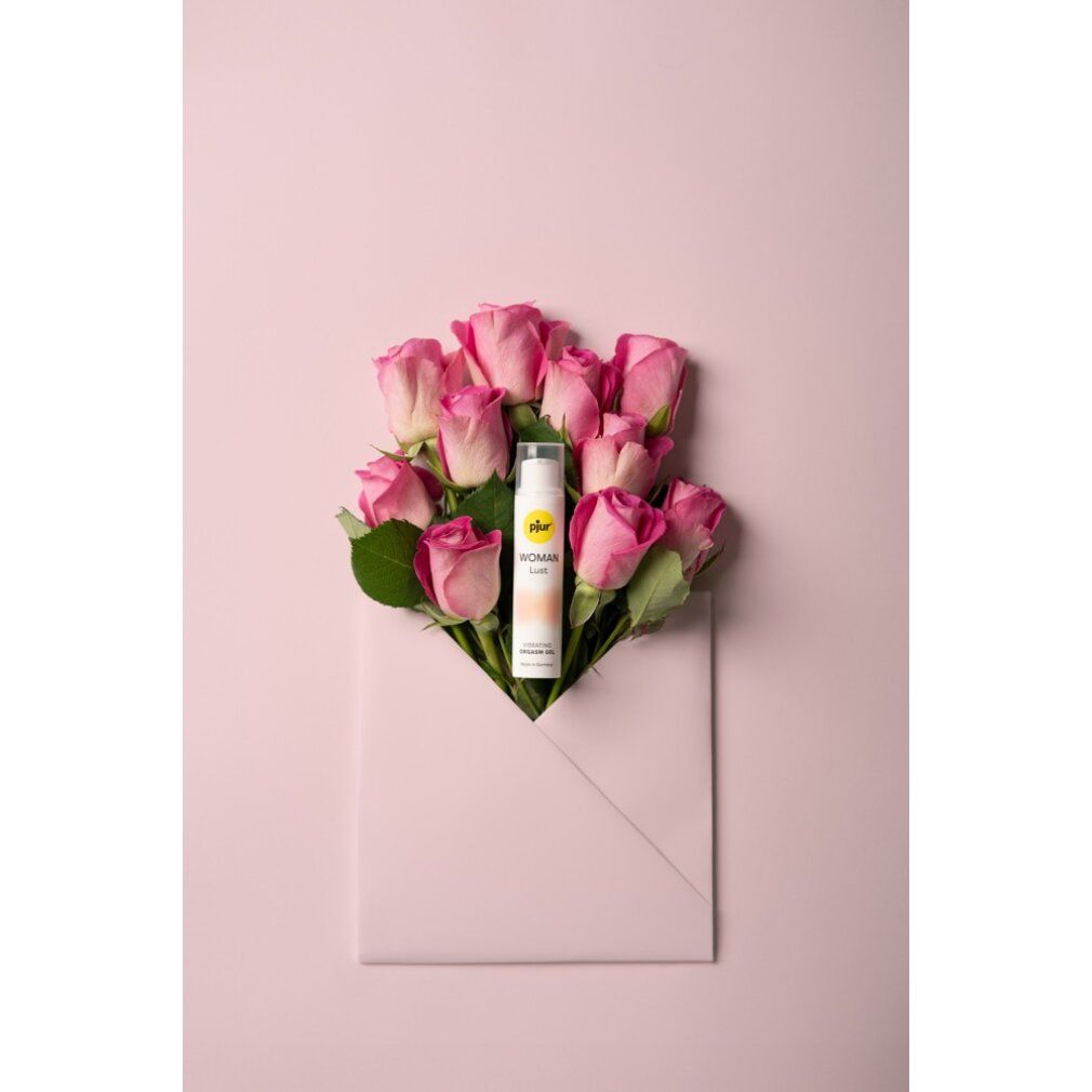 Weiße Flasche mit gelbem Logo und Produktnamen. Text: WOMAN Lust, Vibrating Orgasm Gel. Umgeben von rosa Rosen in einem Umschlag.
