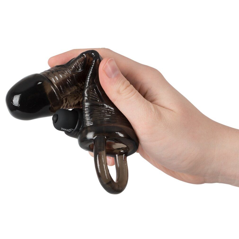 Schwarzes Verlängerungsstück in einer Hand gehalten. Ring, Noppen und Aufsatz sichtbar. Aus Silikon.