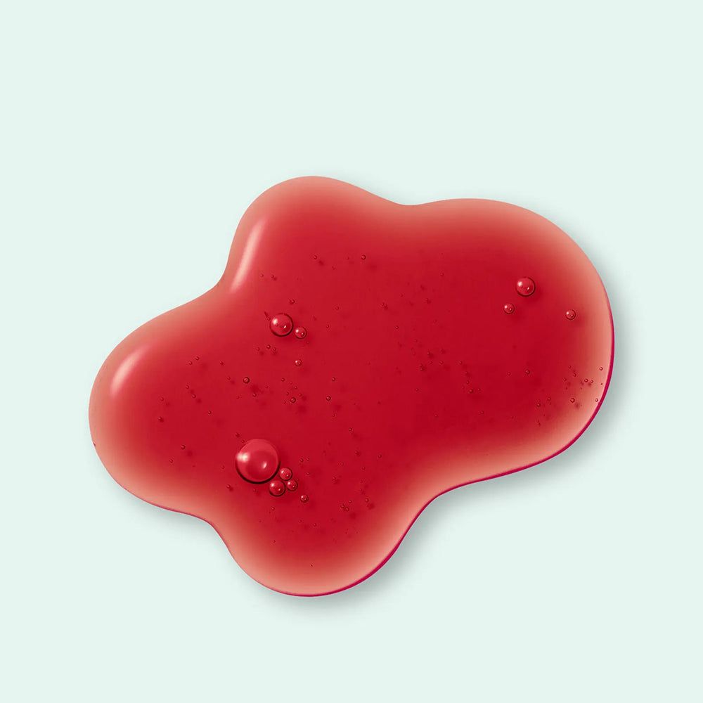 Roter, tropfenförmiger Flüssigkeitsfleck mit Bläschen auf hellblauem Hintergrund.