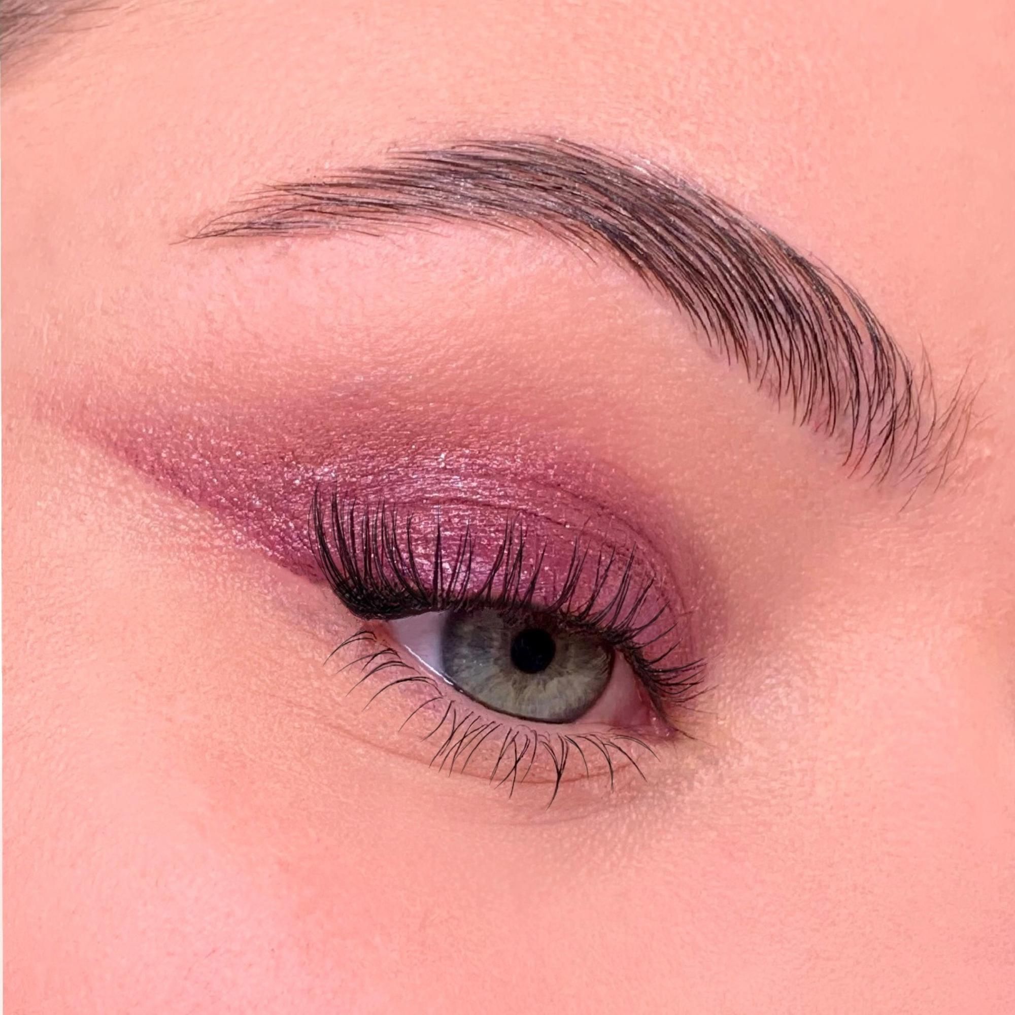 Nahaufnahme eines Auges mit Lidschatten. Augenlid mit pinkfarbenem Lidschatten betont. Wimpern verlängert.