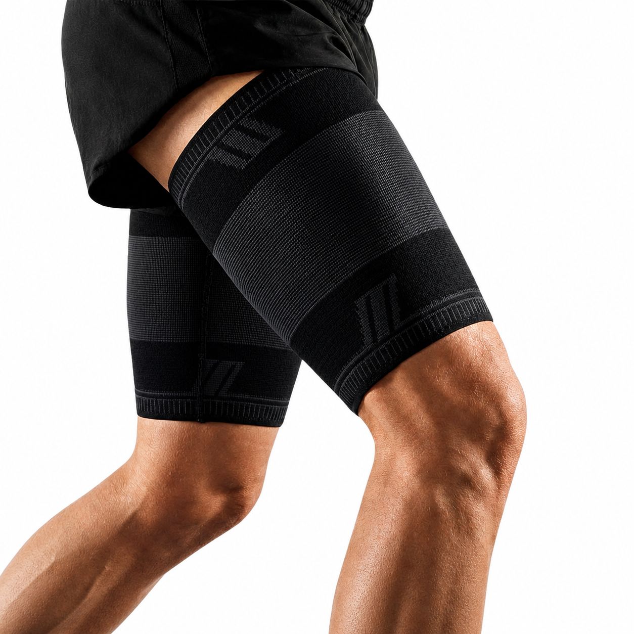 Nahaufnahme einer schwarzen Oberschenkelbandage am Bein. Schwarze Sportkleidung. Weißer Hintergrund.