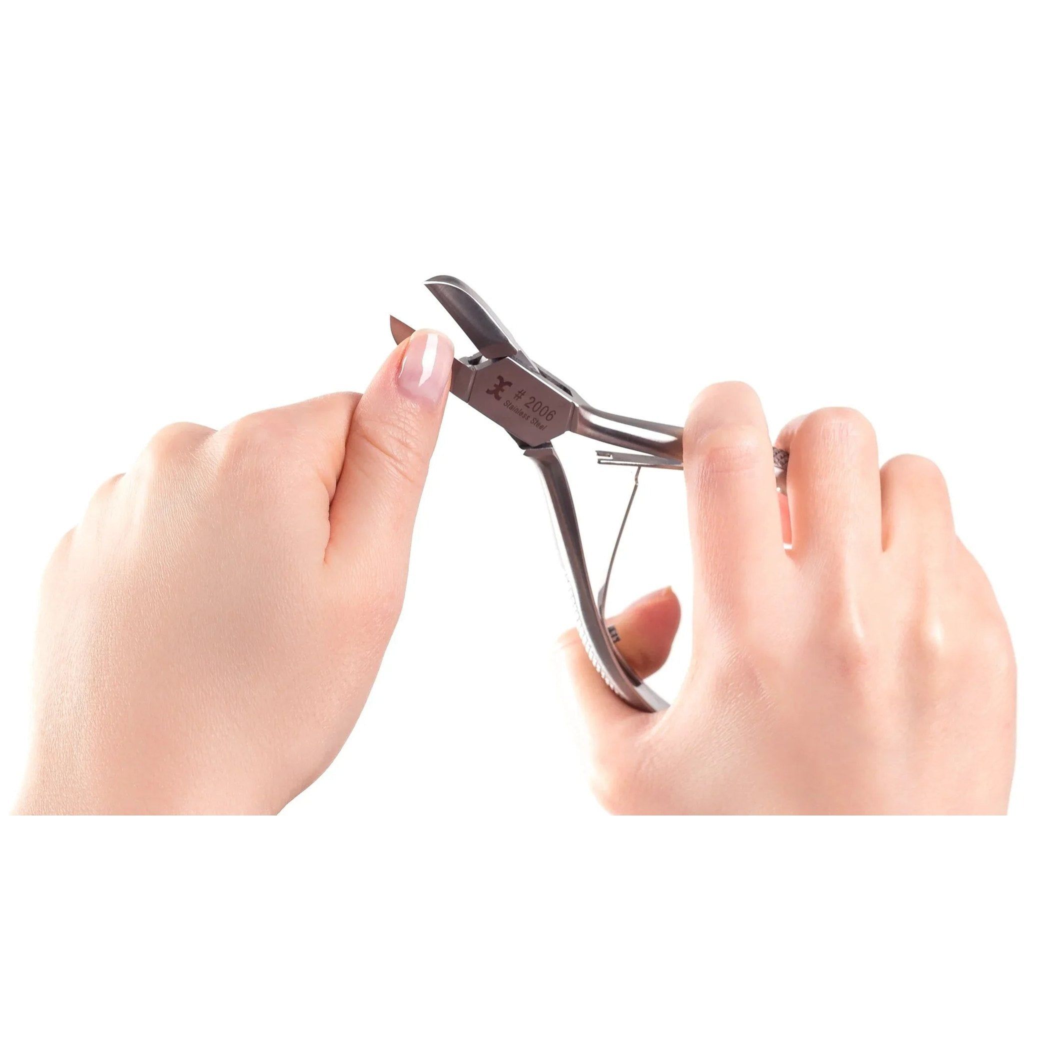 Nagelzange in Anwendung. Hände halten die Zange und bearbeiten einen Nagel. Weißer Hintergrund.