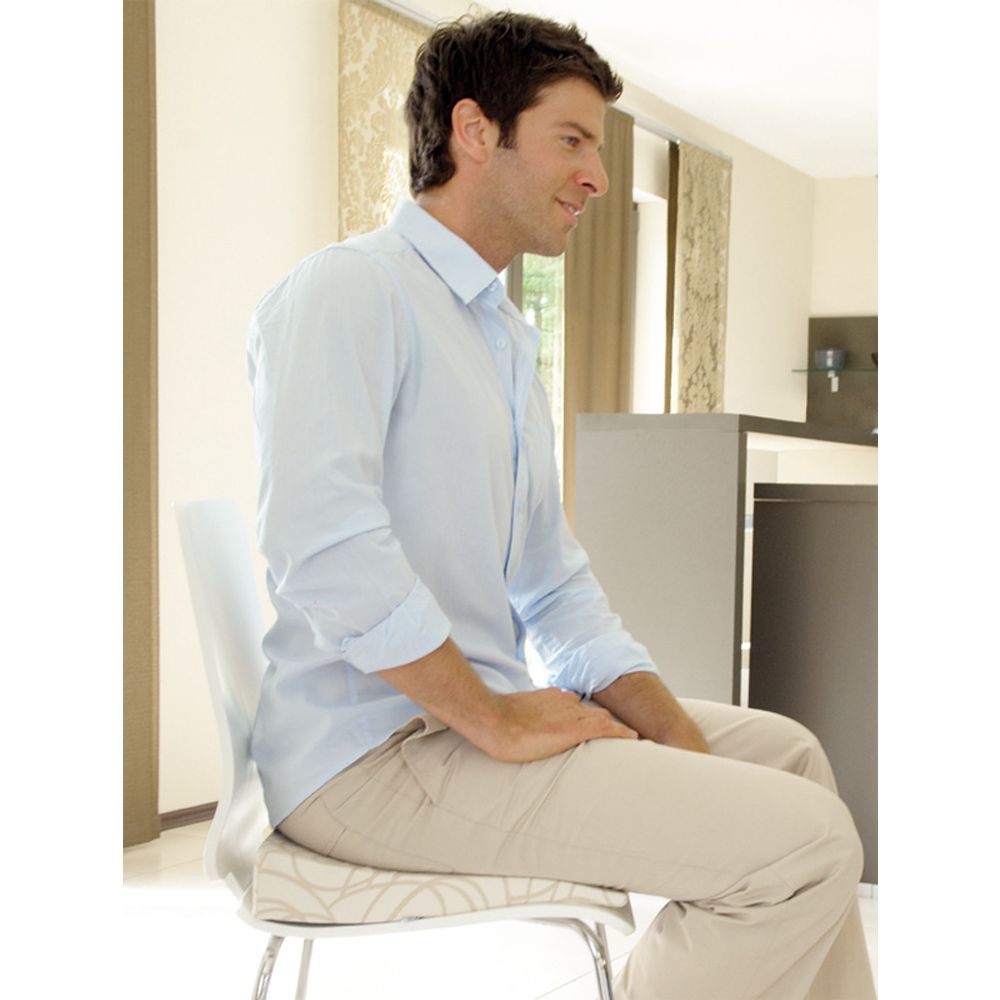 Mann sitzt auf Stuhl mit hellem Kissen. Kissen mit Muster, Mann in hellem Hemd.