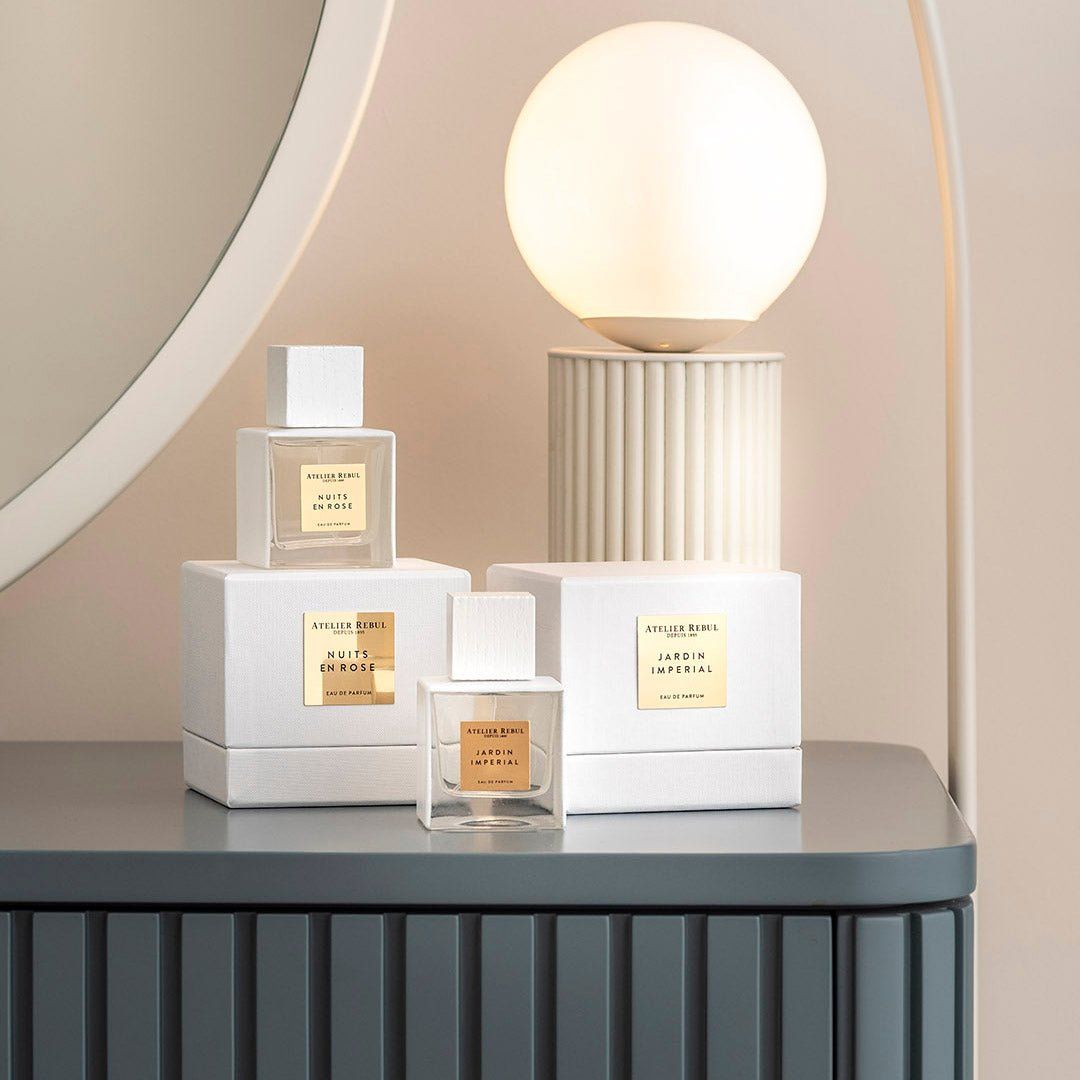 Parfümflakons auf weißen Boxen. Auf einem Schrank, mit Spiegel und Lampe im Hintergrund.