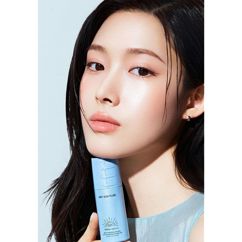 Frau hält TFIT Airy Sun Fluid Flasche mit SPF50+ PA++++.
