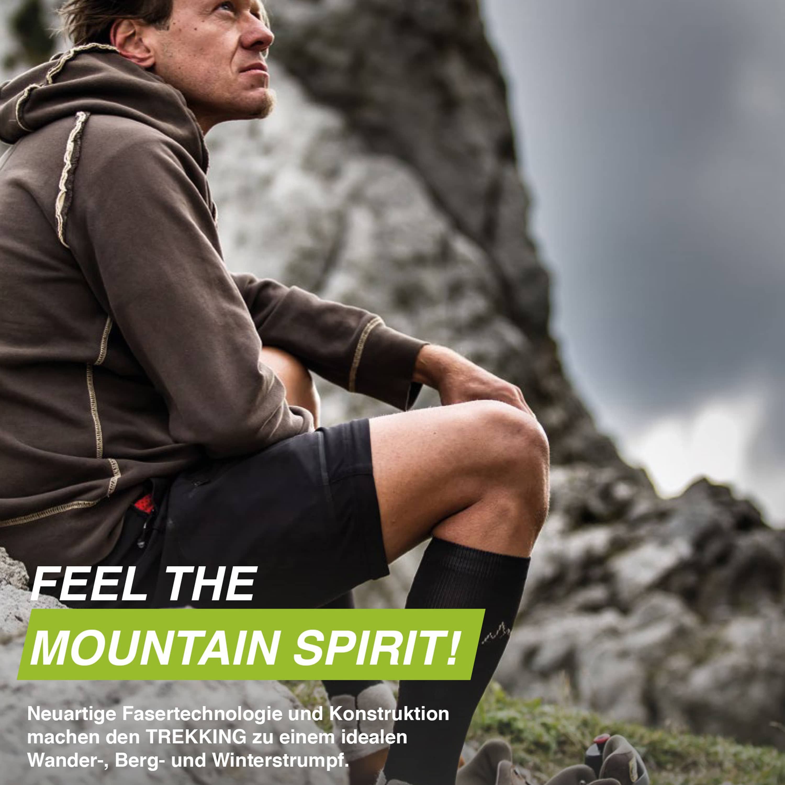Mann sitzt auf Felsen, trägt schwarze Kompressionsstrümpfe. Text: "FEEL THE MOUNTAIN SPIRIT!".