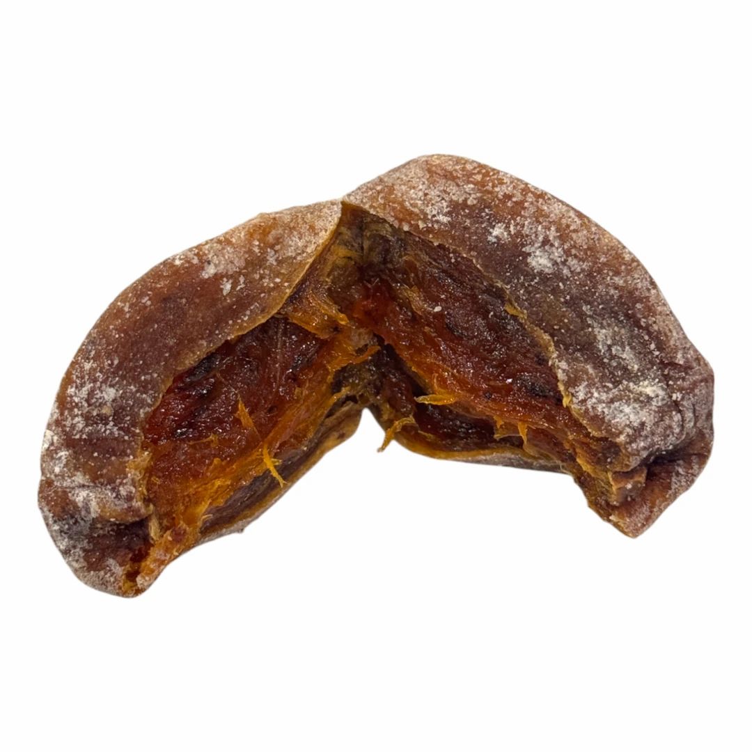 Zwei Hälften einer getrockneten Kaki-Frucht. Die Frucht hat eine braune Farbe und eine leicht runzlige Oberfläche.