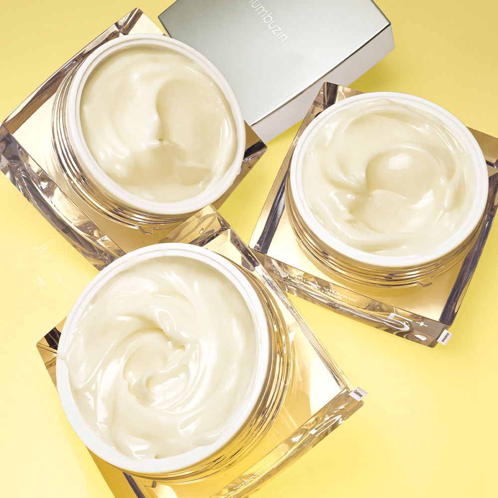 Drei offene Tiegel mit NUMBUZIN Nr.5 Vitamin Glutathione Dark Spot Laser Creme auf gelbem Hintergrund.