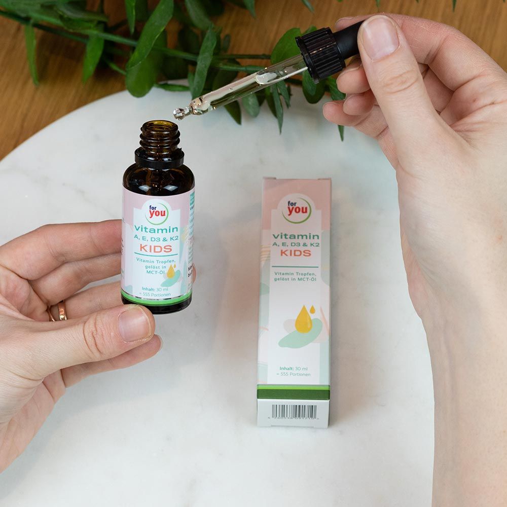 Hände halten Flasche und Pipette mit Vitamin-Tropfen.