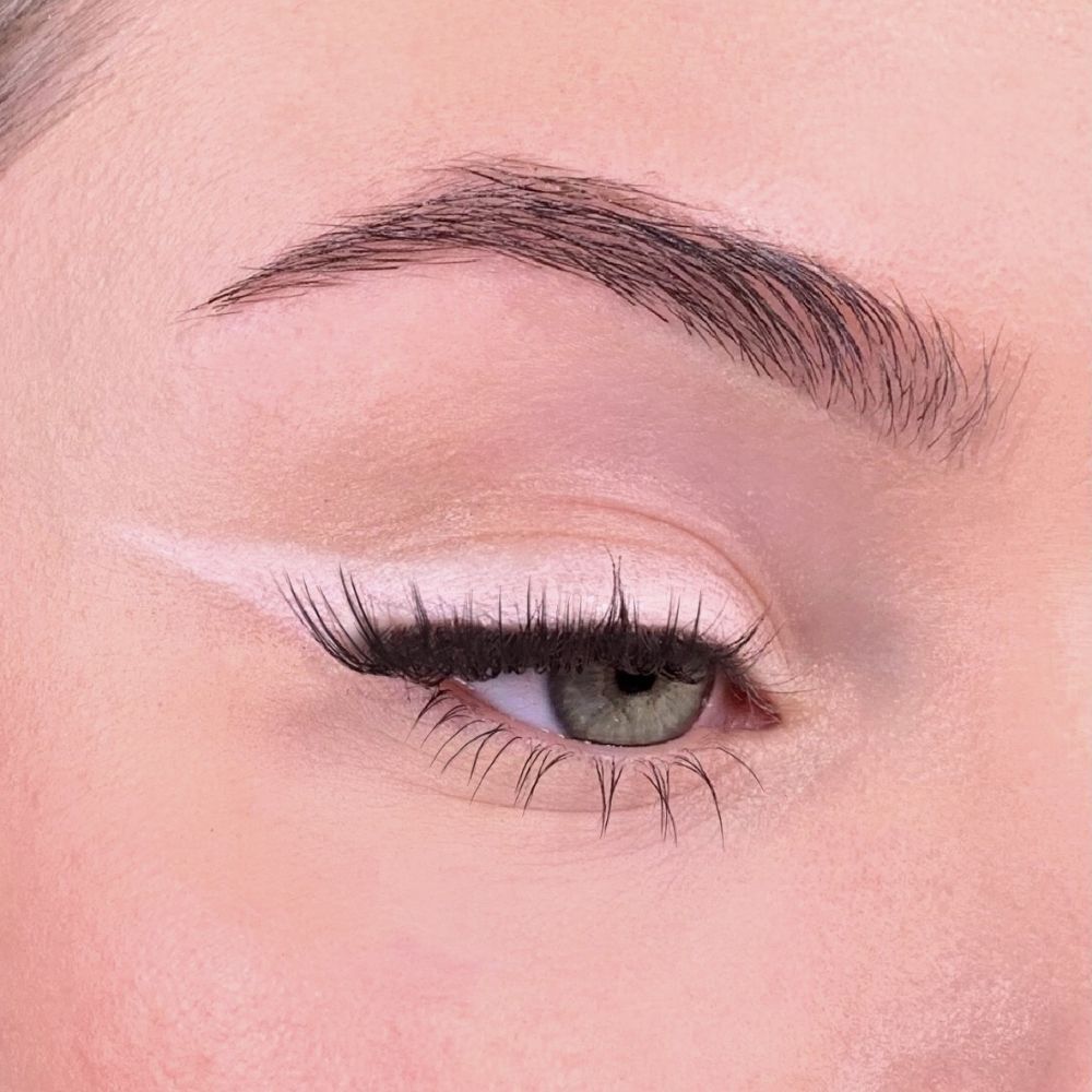 Auge mit rosa Lidschatten. Rosa Linie auf dem Augenlid. Braue und Wimpern sichtbar.