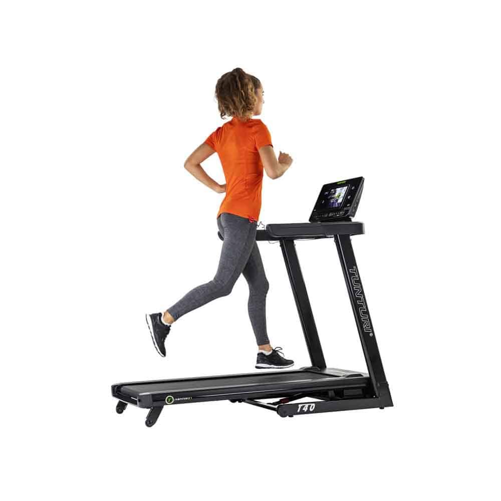 Person läuft auf einem schwarzen Tunturi Laufband T40 Competence. Frau in Sportkleidung. Display mit Trainingsdaten. Tunturi-Logo am Rahmen.