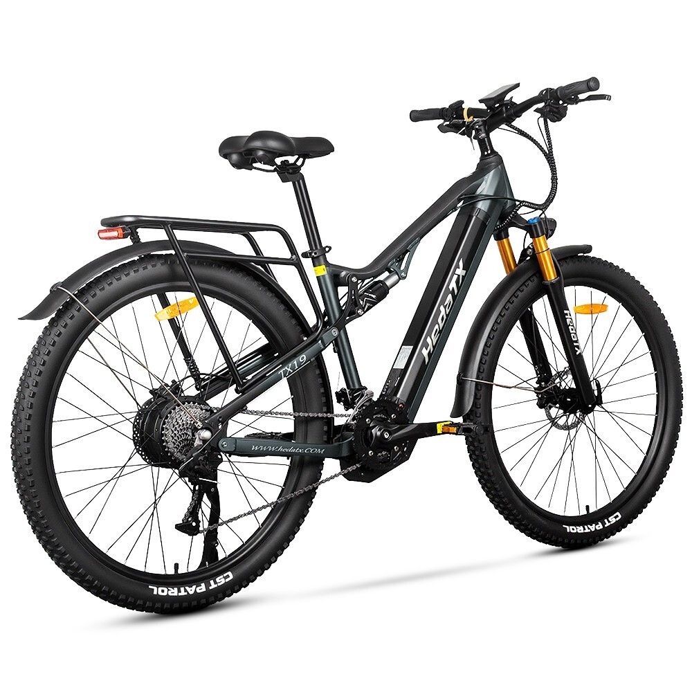Graues E-Bike HedaTX TX19. Schwarze Reifen, Gepäckträger, Federung. Gelbe Gabel. 27 Gänge. Aufschrift HedaTX.