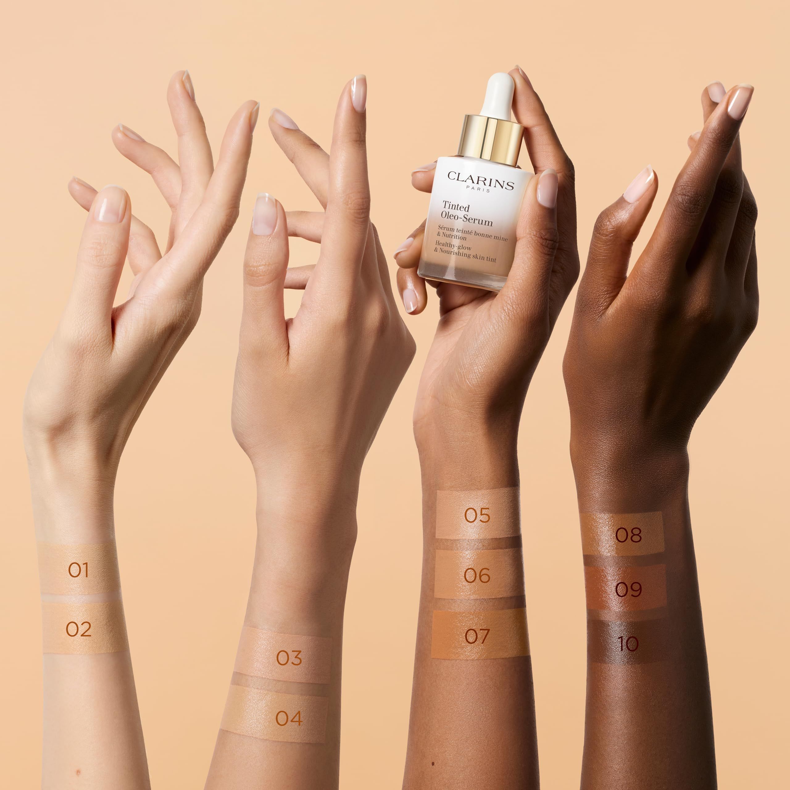 Hände mit Farbtönen. Arme mit verschiedenen Hauttönen, nummeriert 01-10. Clarins Oleo-Serum auf einer Hand.