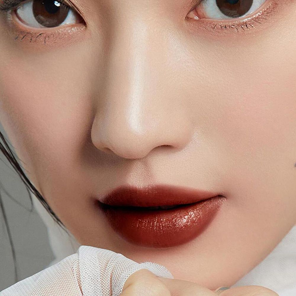 Nahaufnahme von Lippen mit braunem Lippenstift. Hautton. Weiße Kleidung. Augenbrauen und Augen sichtbar.