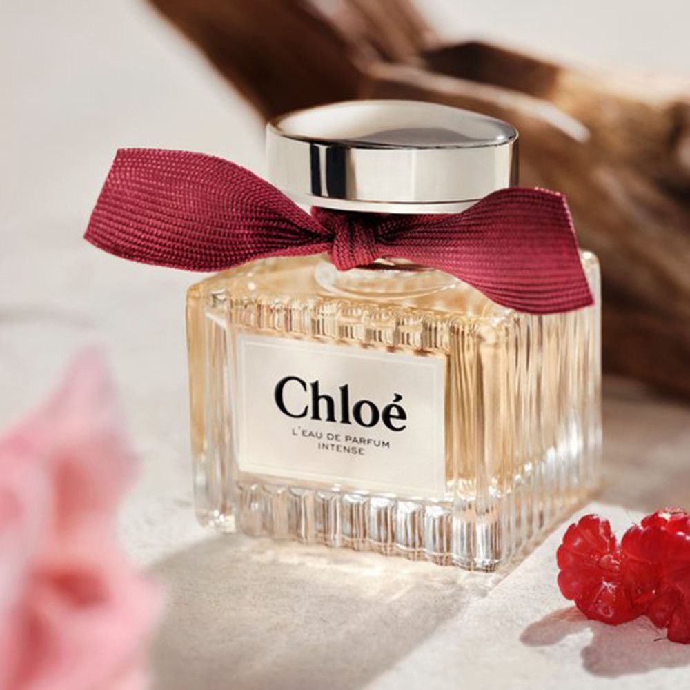 Chloé L'Eau de Parfum Intense Flakon mit Schleife. Glasflakon mit Schriftzug. Himbeer-Dekoration.