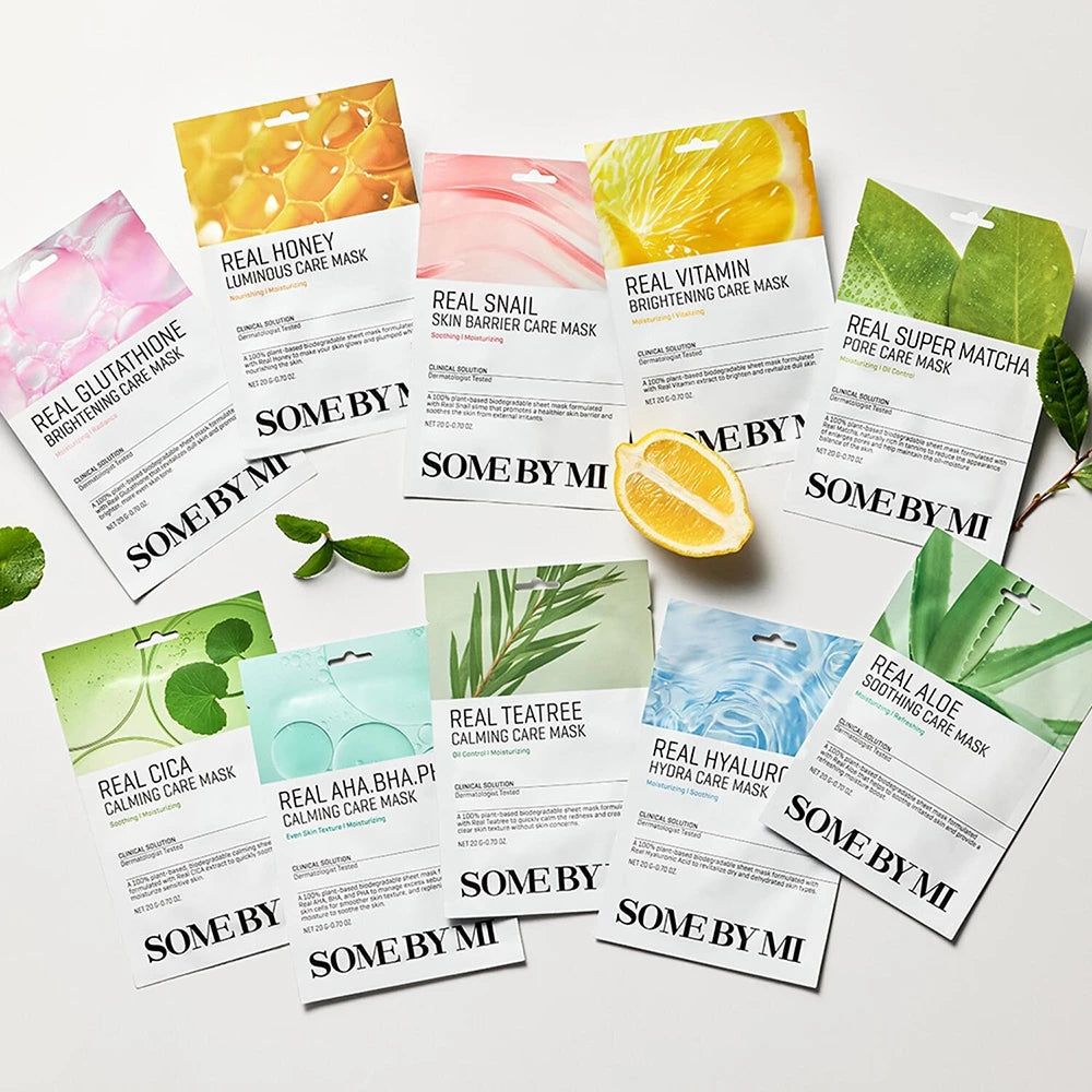 Verschiedene SOMEBYMI Gesichtsmasken. Verpackungen mit verschiedenen Designs und Inhaltsstoffen. Zitrone und Blätter daneben.