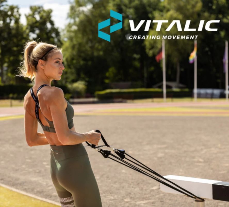 Fitnessband mit Griffen. Frau trainiert im Freien. VITALIC Logo.