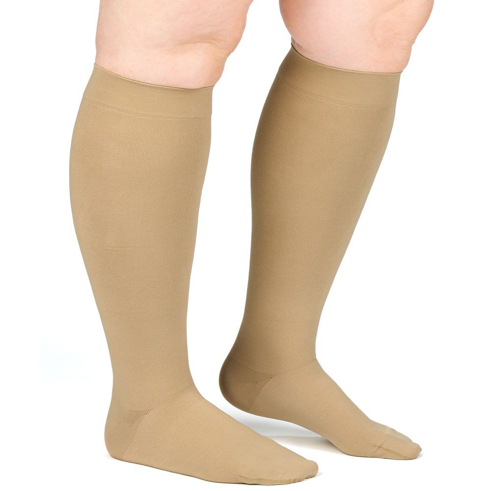 Hautfarbene Kompressionsstrümpfe am Bein. Feines Material, bis zum Knie reichend. Zehenbereich geschlossen.