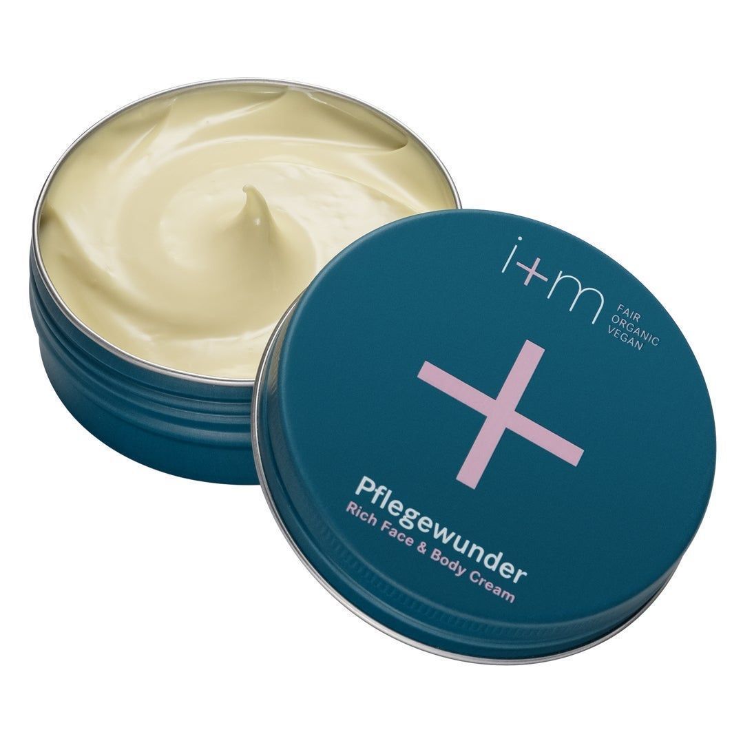 Offene Dose mit i+m Naturkosmetik Pflegewunder Rich Face & Body Cream. Blaue Dose mit rosa Kreuz.