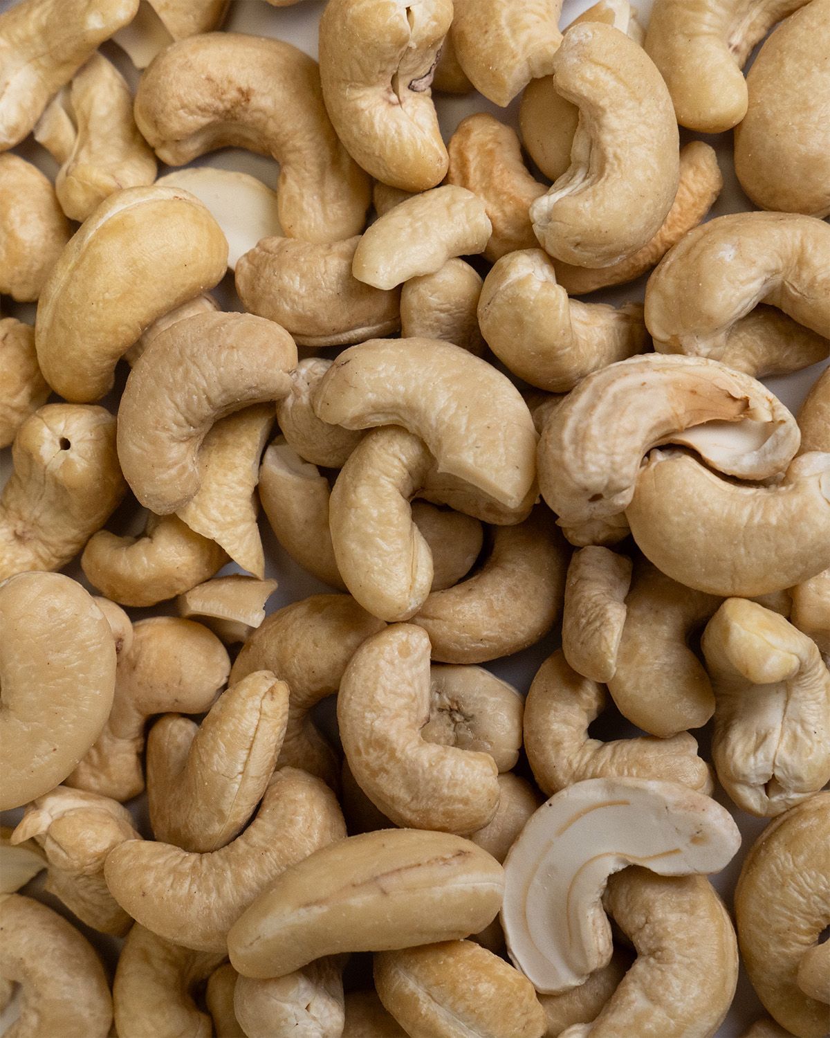 Nahaufnahme von Cashewkernen. Die Kerne sind hellbraun und haben eine gebogene Form.