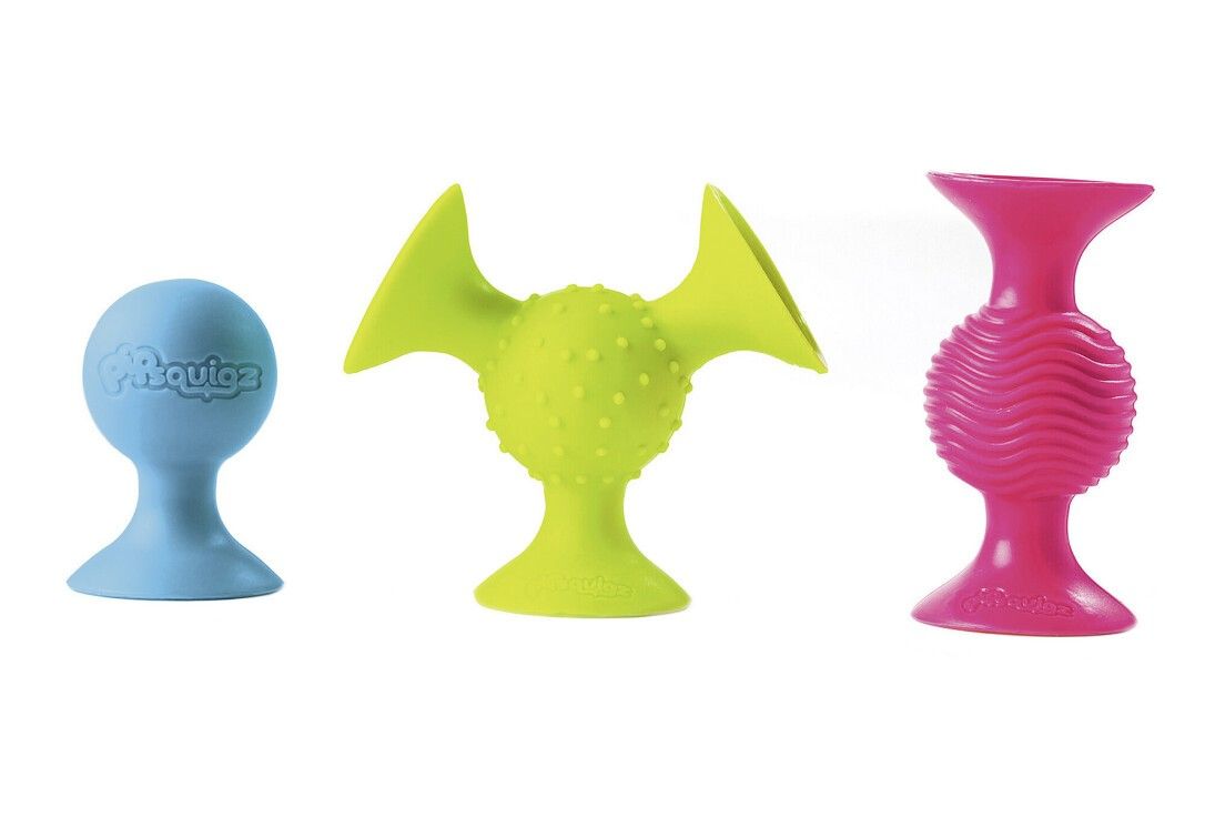 Drei verschiedenfarbige Saugnäpfe. Blau, grün und pink. Der blaue hat den Schriftzug "pipSquigz". Der grüne hat eine strukturierte Oberfläche.