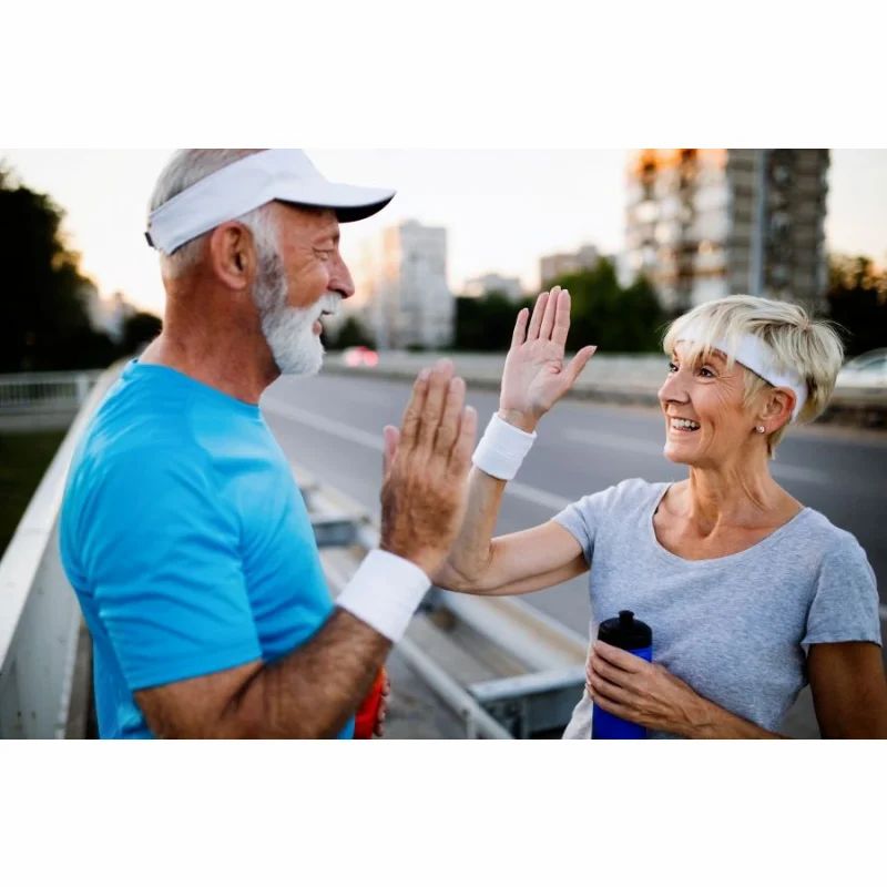 Zwei ältere Menschen geben sich High Five. Beide tragen Sportkleidung und Stirnbänder.