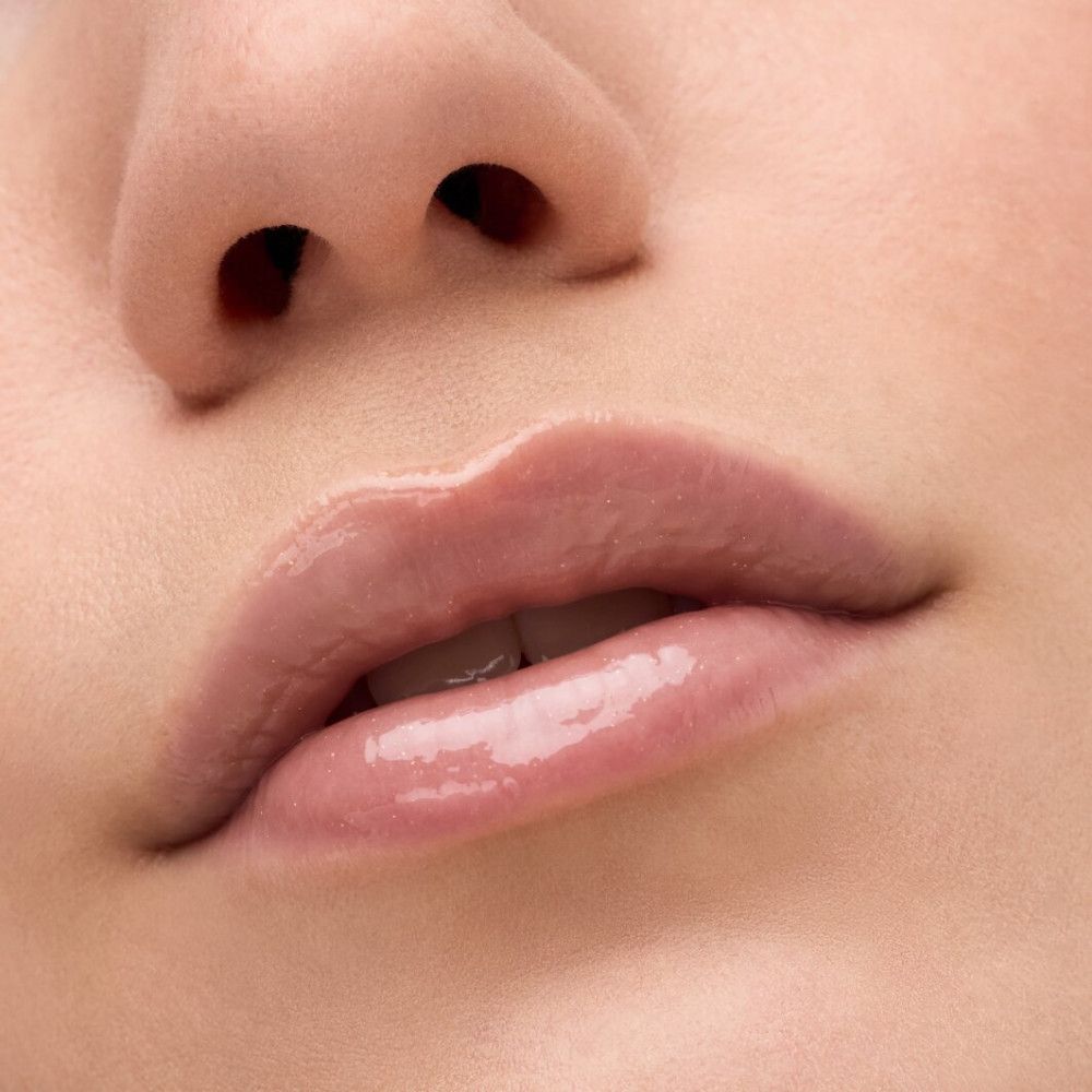 Nahaufnahme von Lippen mit Lip Elixir. Glänzender, rosafarbener Glanz auf den Lippen.