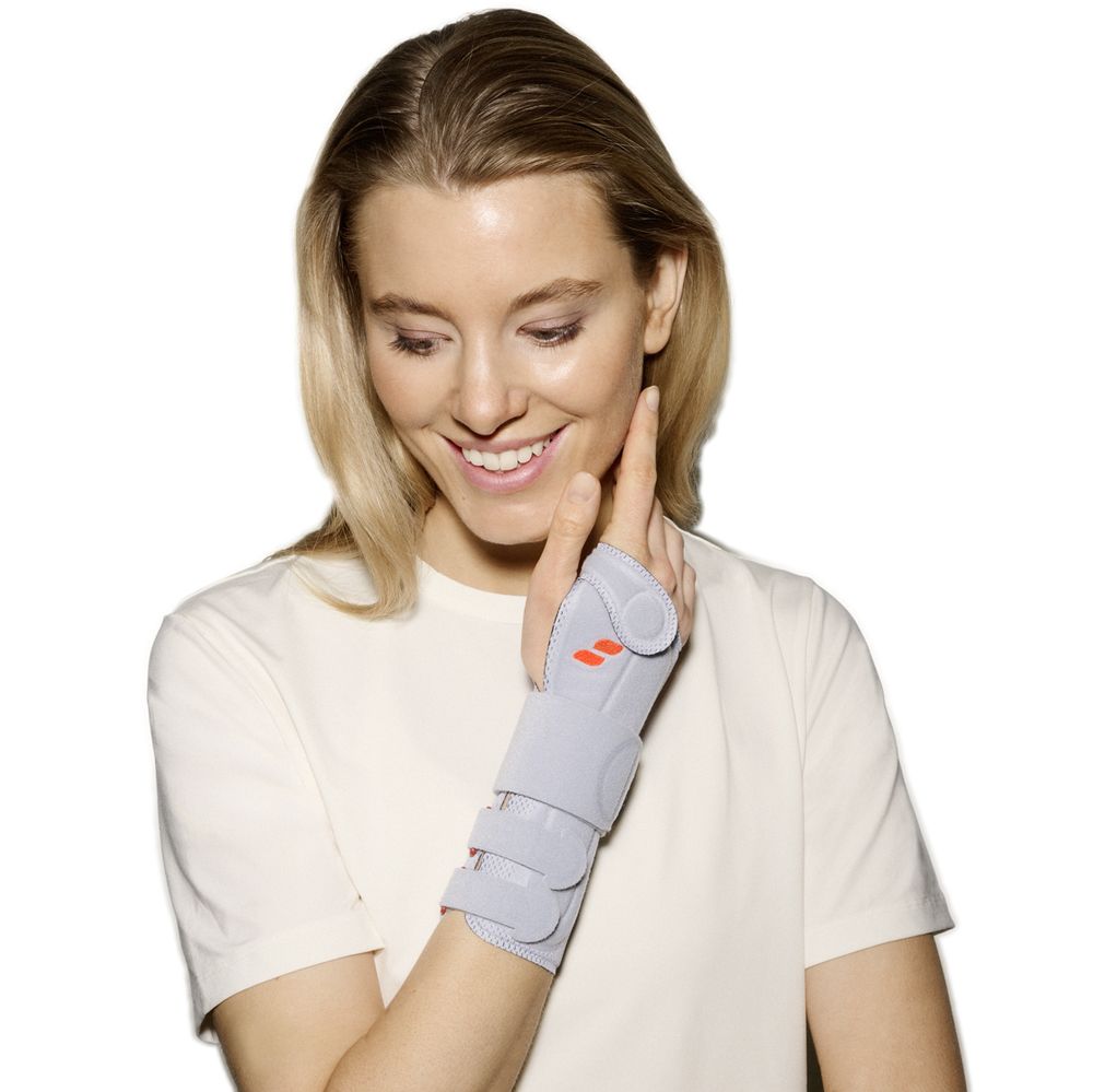 Frau trägt eine graue Handgelenkbandage mit Klettverschlüssen und orangen Akzenten.