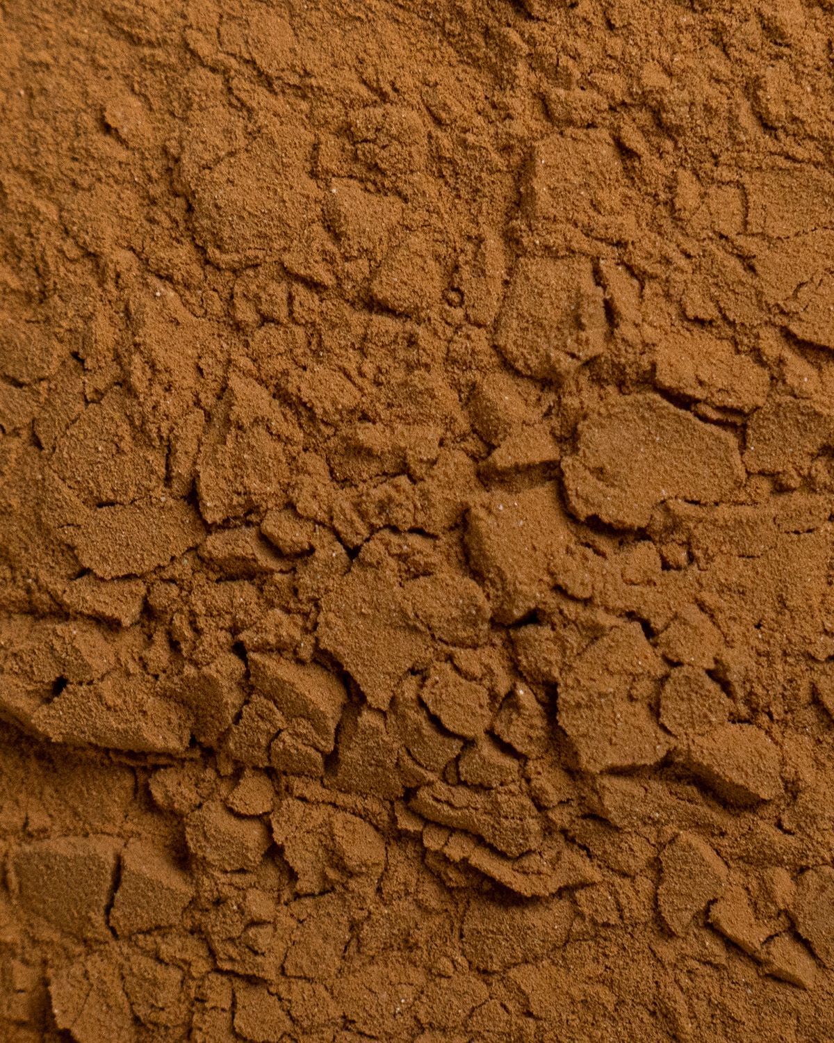 Nahaufnahme von braunem Guarana Extrakt Pulver. Die Textur ist grob und körnig.