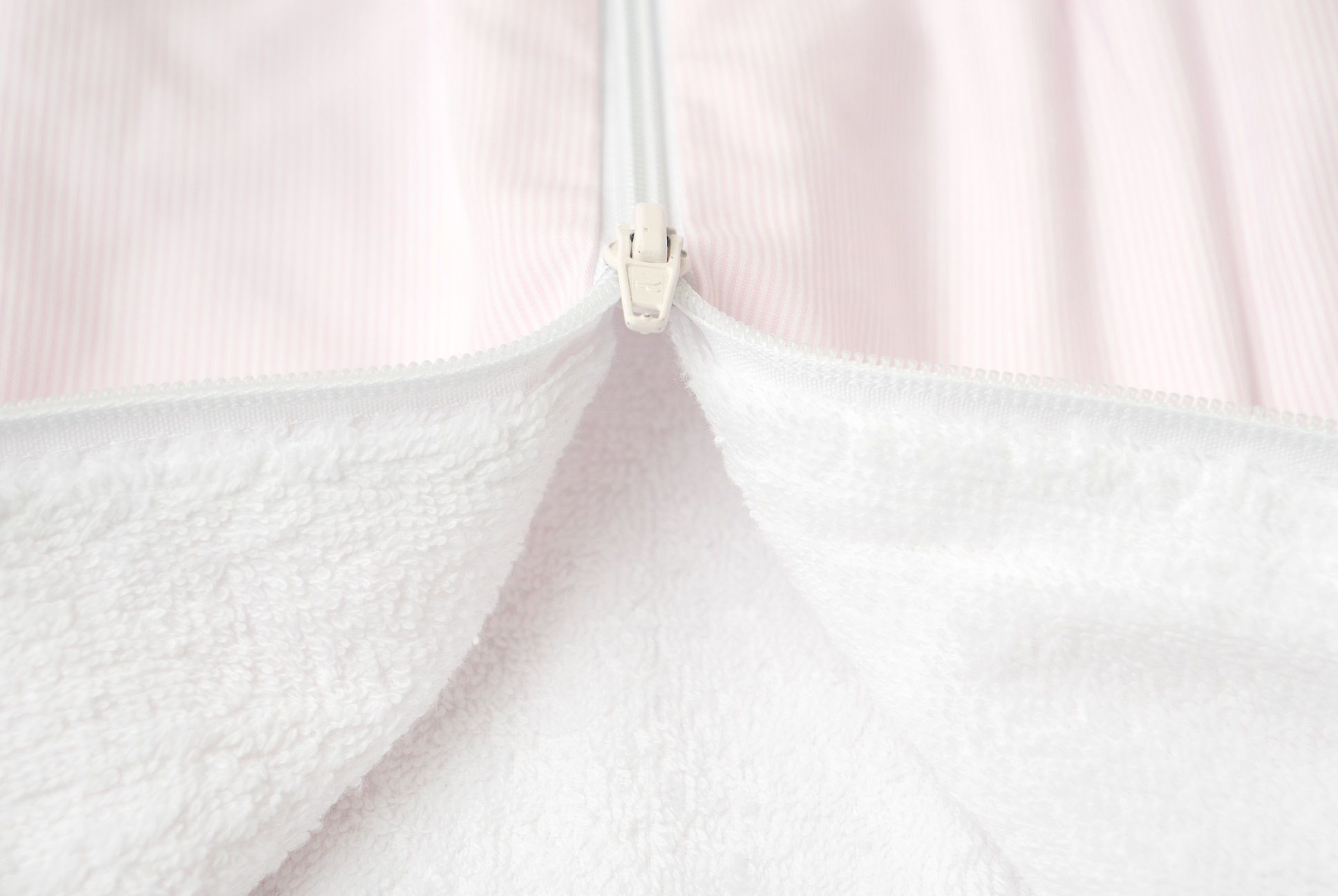 Nahaufnahme des Reißverschlusses eines rosa Schlafsacks. Weißer Reißverschluss, Frottee-Innenfutter.