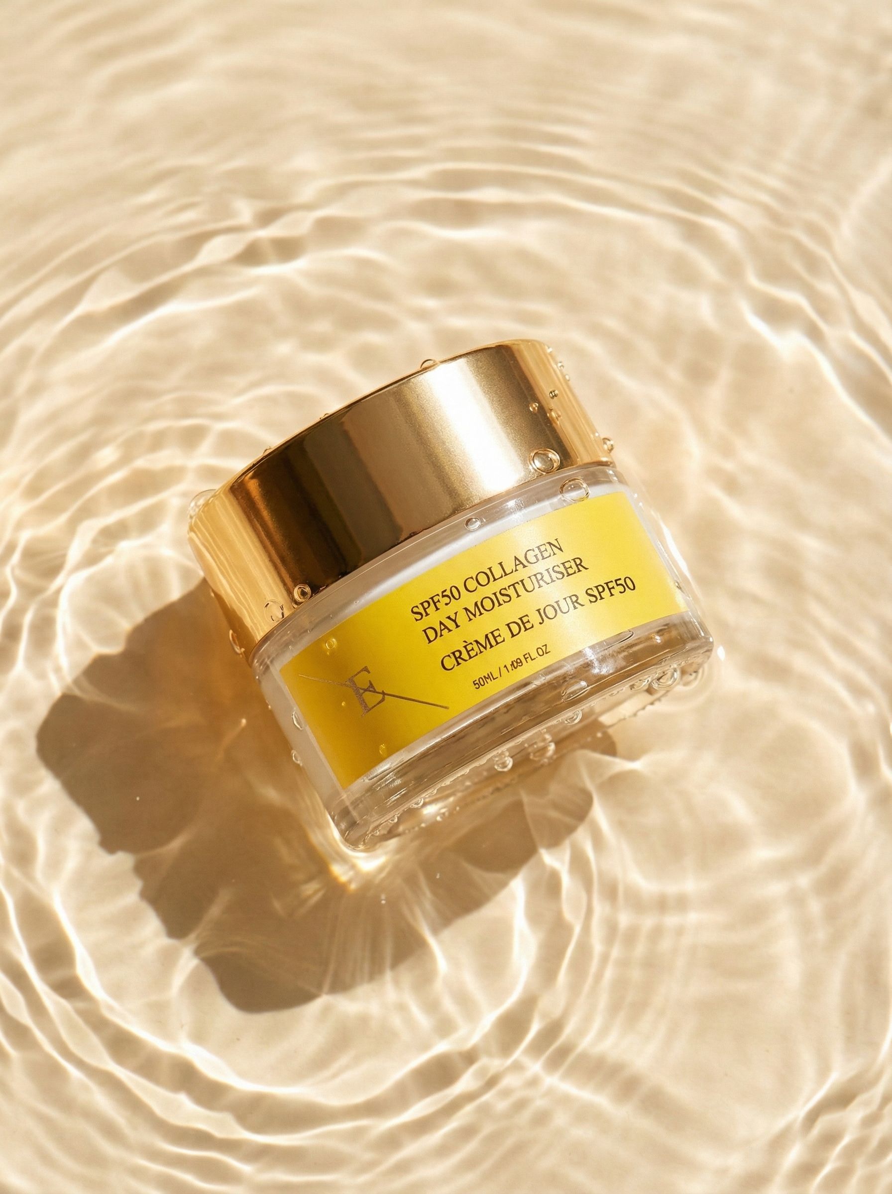 Creme-Glas mit goldenem Deckel in Wasser. Gelbes Etikett mit Text: SPF50 Collagen Day Moisturiser, Crème de Jour SPF50. Wasserwellen.
