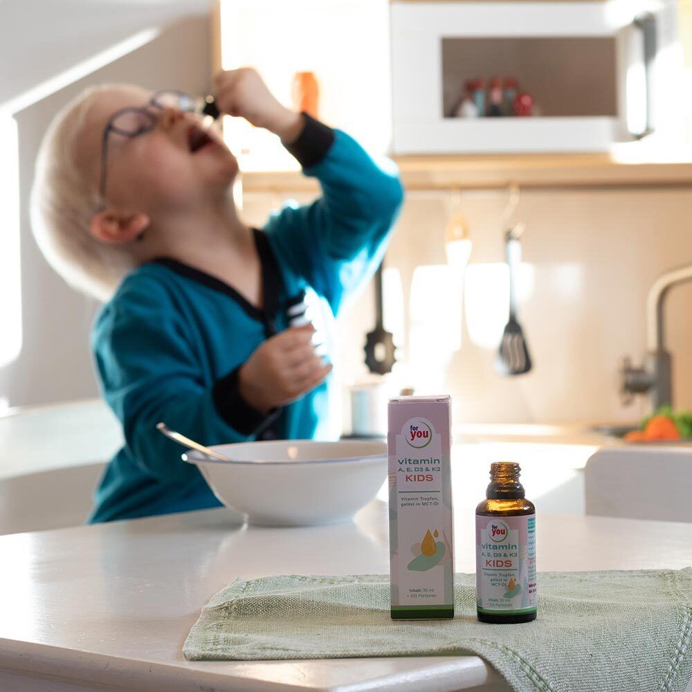 Kind nimmt Vitamin-Tropfen aus Pipette in der Küche ein.