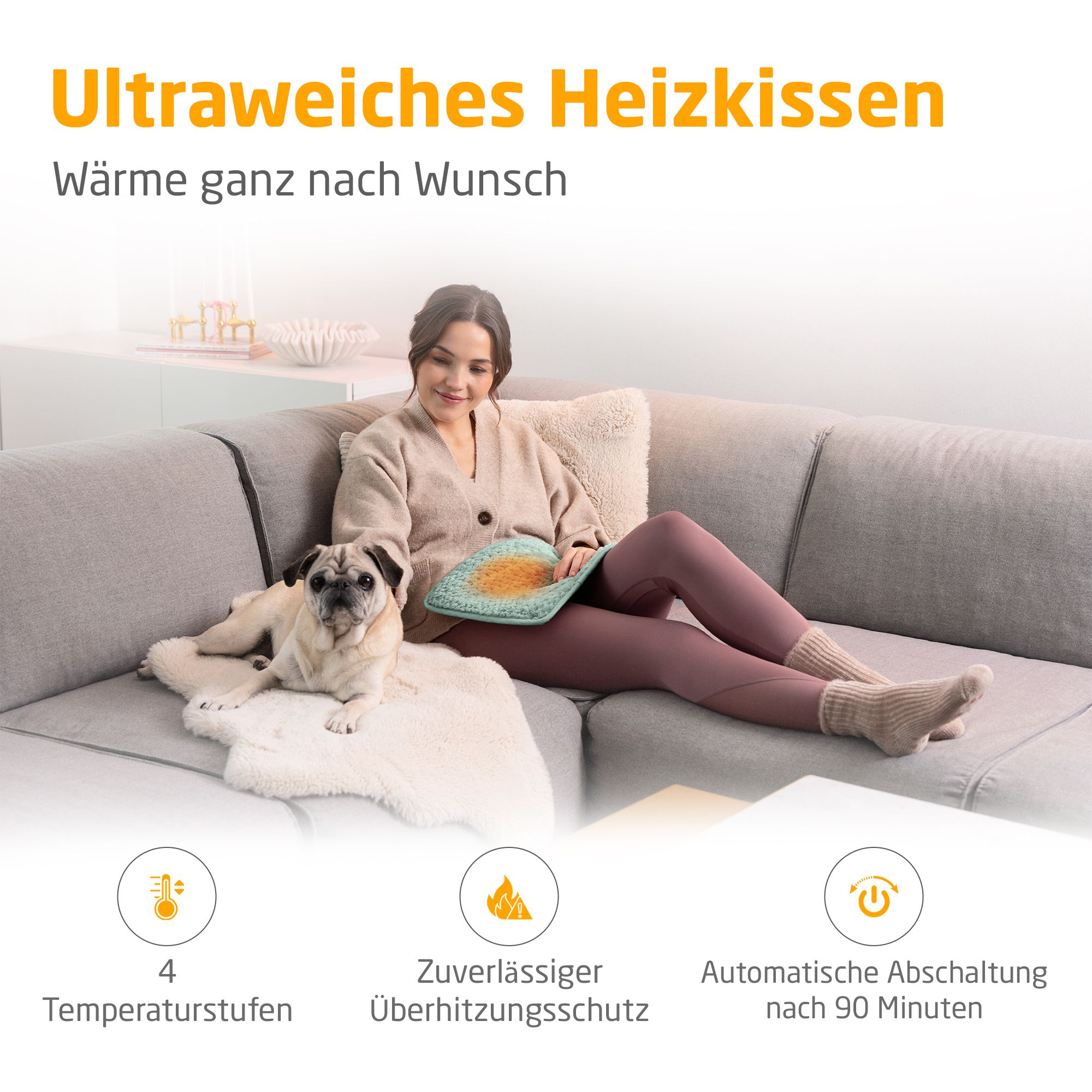 Heizkissen, grün. Frau sitzt auf Sofa mit Hund. 4 Temperaturstufen, Überhitzungsschutz, automatische Abschaltung nach 90 Minuten.