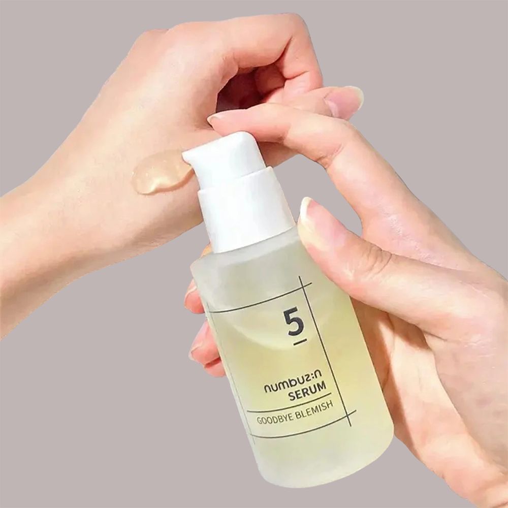 Hände halten Serumflasche. Serum auf Hand aufgetragen. Aufschrift: 5, numbuz:n SERUM, Goodbye Blemish. Flasche mit weißem Pumpkopf.