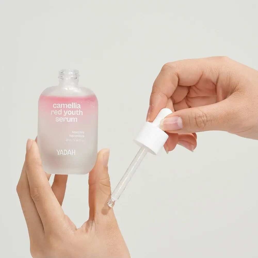 Serumflasche mit Pipette. Aufschrift: Camellia Red Youth Serum. Marke YADAH. Hände halten Flasche und Pipette.