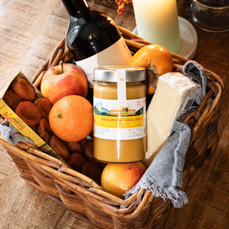 Korb mit ImkerPur Engelwurzhonig (roh), Obst, Käse und Wein. Honigglas mit Etikett.