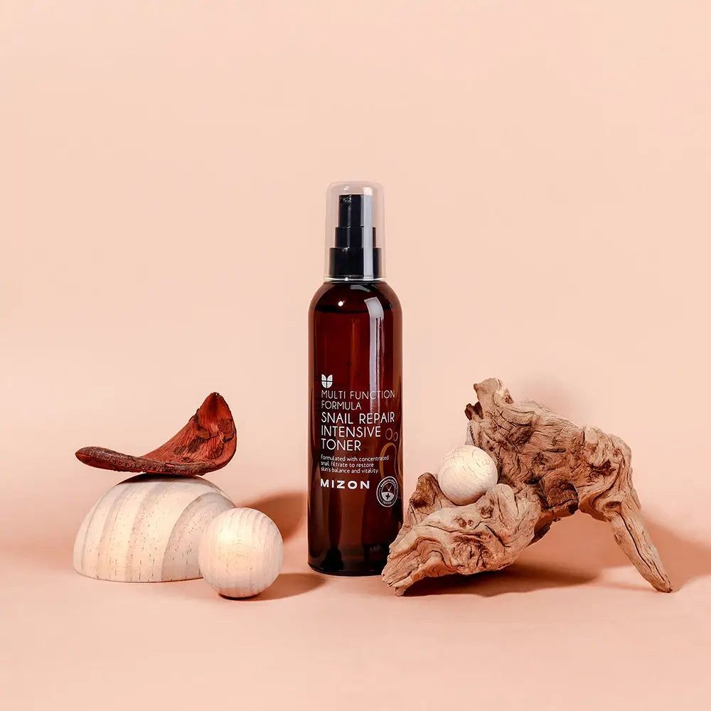 Braune Flasche mit Zerstäuber, umgeben von Holz und Dekoration. Aufschrift: MIZON Snail Repair Intensive Toner.