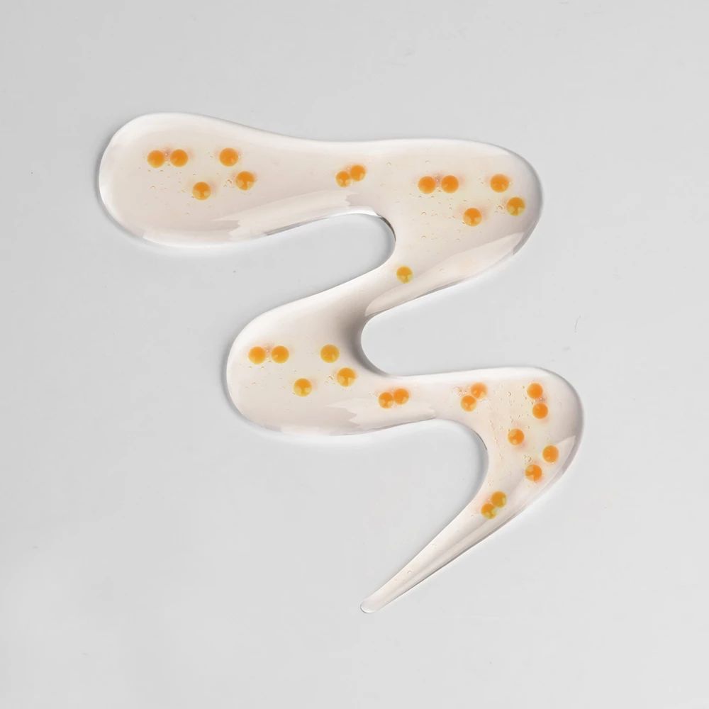 Transparente Flüssigkeit mit gelben Kügelchen. In wellenförmiger Form auf hellem Untergrund.