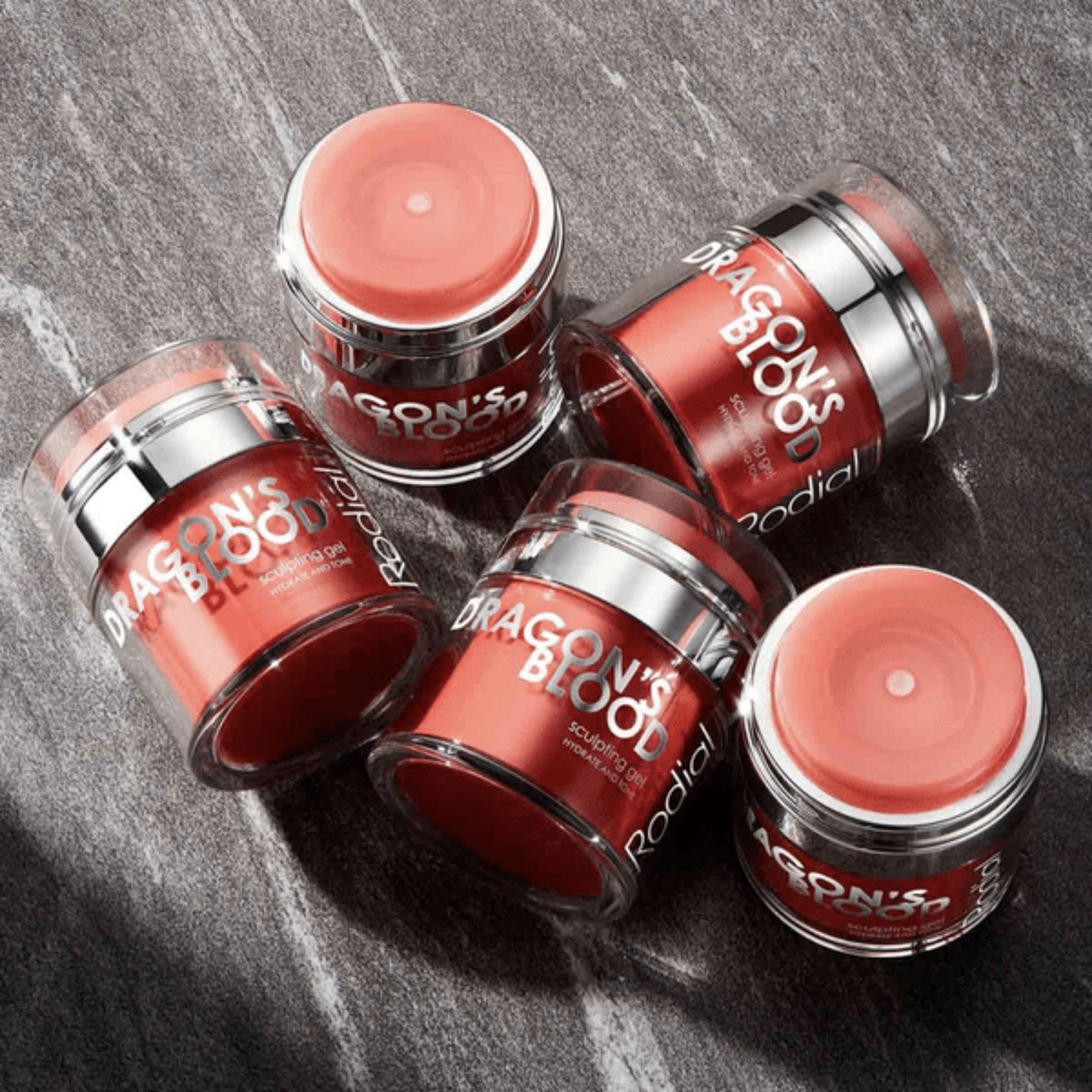 Fünf rote Tiegel mit silbernen Deckeln. Aufschrift: DRAGON'S BLOOD, Sculpting Gel. Auf Marmoroberfläche.