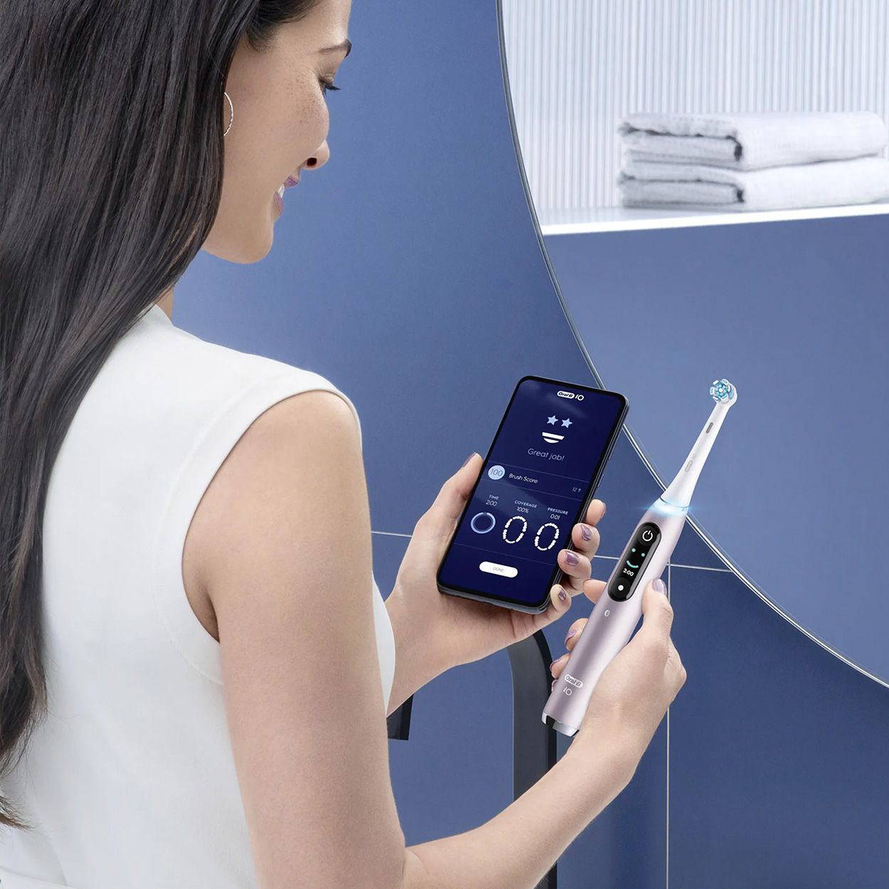 Frau mit Zahnbürste und Smartphone. Auf dem Smartphone-Bildschirm ist die Oral-B-App zu sehen.