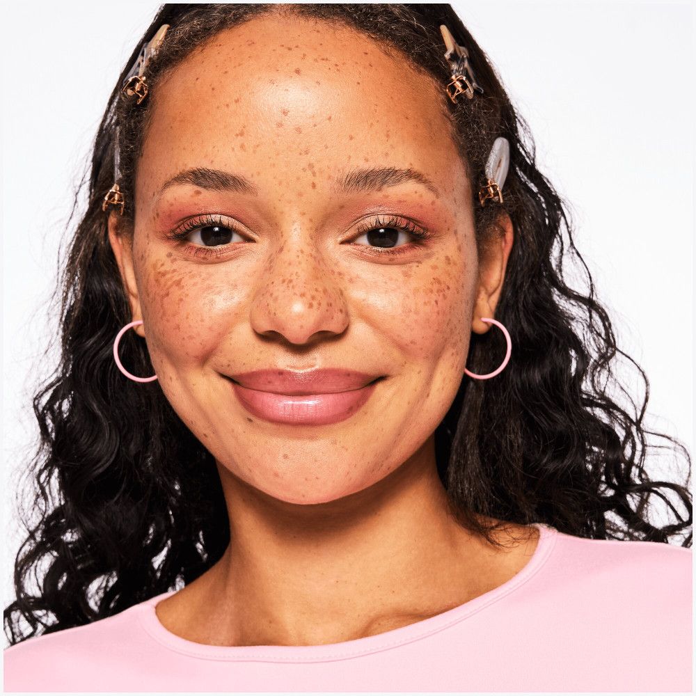 Porträt einer Frau mit Lippenstift, Ohrringen und Haarspangen. Haut mit Sommersprossen.