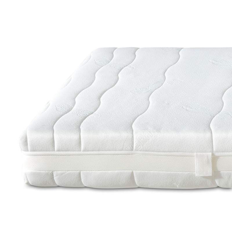 Weiße Matratze mit wellenförmiger Steppung. Seitlich ein weißes Band mit Anhänger.