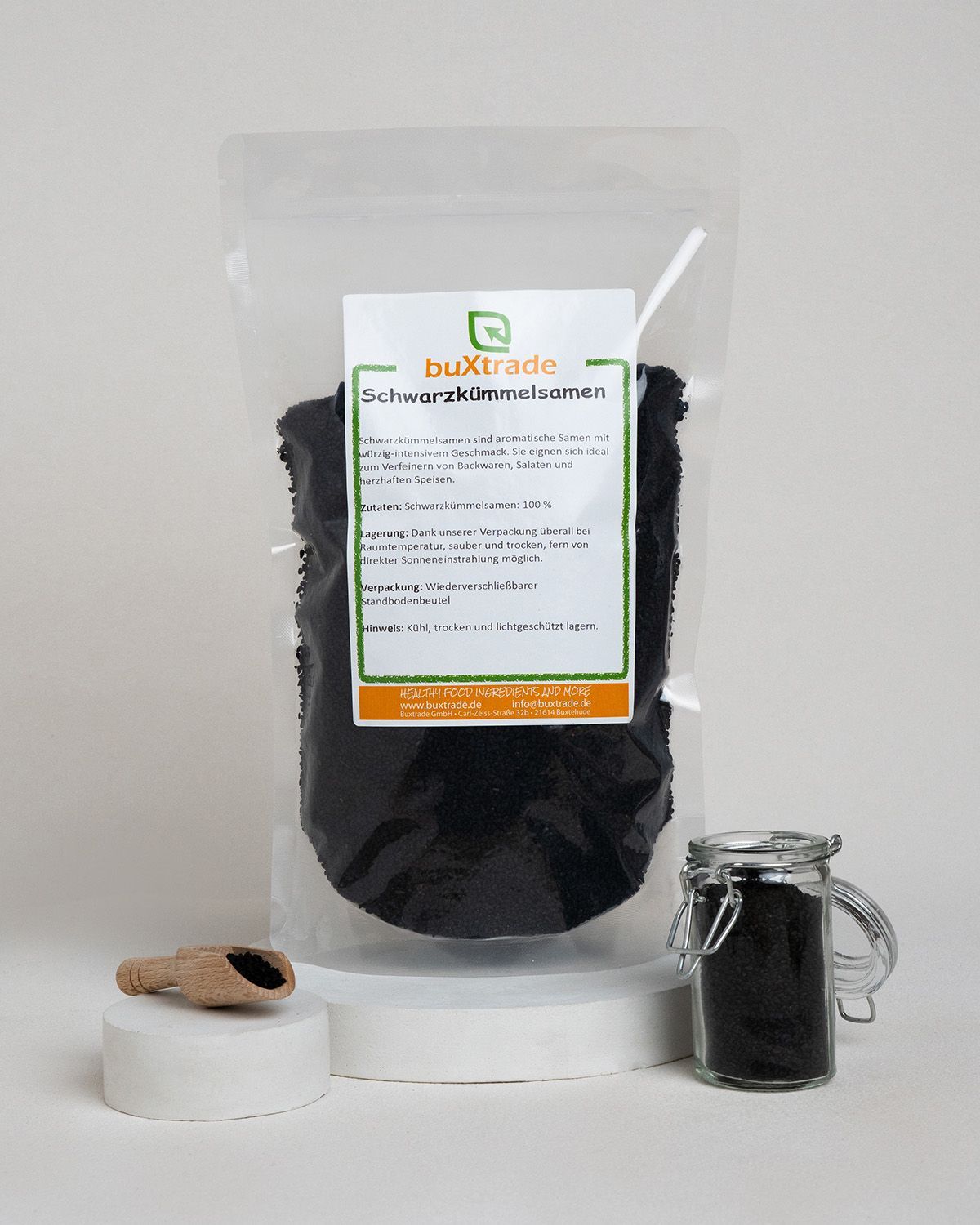 Verpackung mit buXtrade Schwarzkümmelsamen, Holzschaufel und Glas.