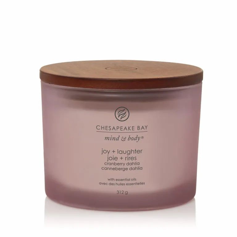 Rosafarbene Kerze mit Holzdeckel. Aufschrift: Chesapeake Bay, mind & body, joy + laughter, joie + rires, cranberry dahlia, canneberge dahlia. Mit ätherischen Ölen.
