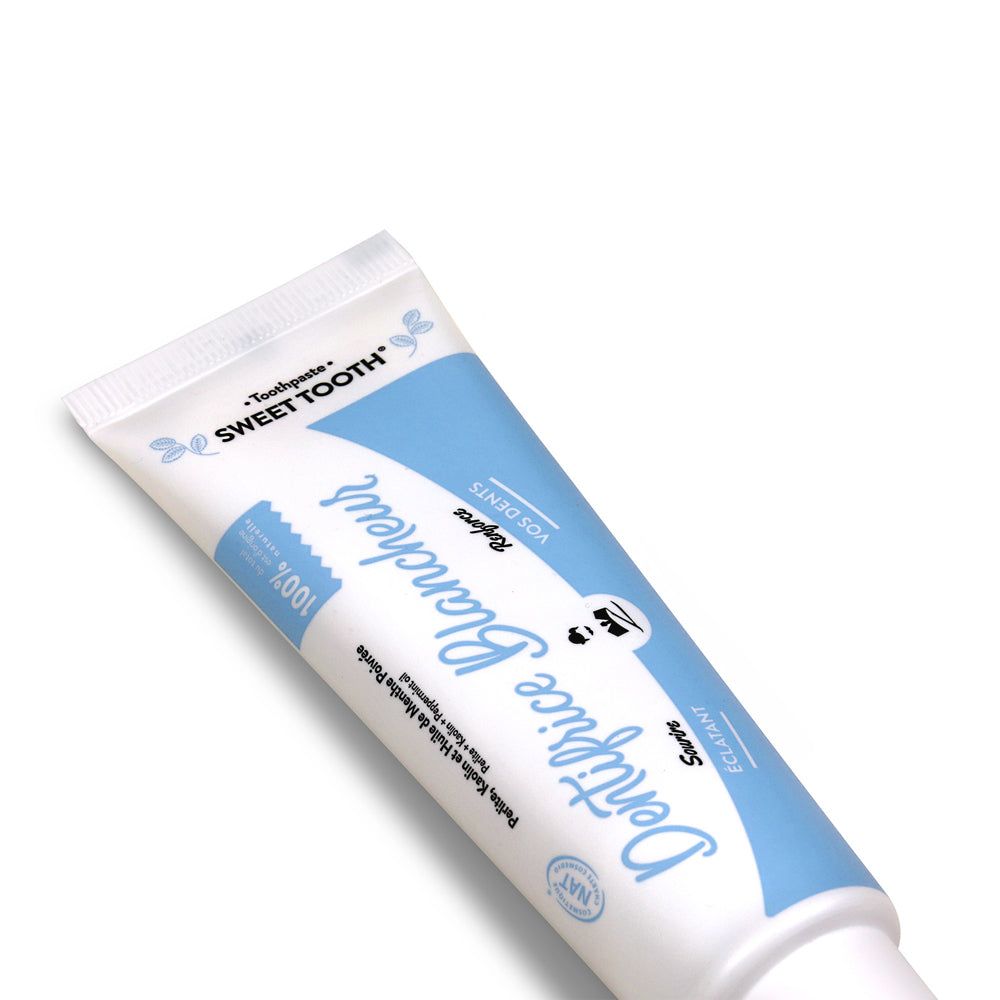 Zahncreme-Tube, weiß-blau. Aufschrift: "Dentifrice Blancheur", "Sweet Tooth".