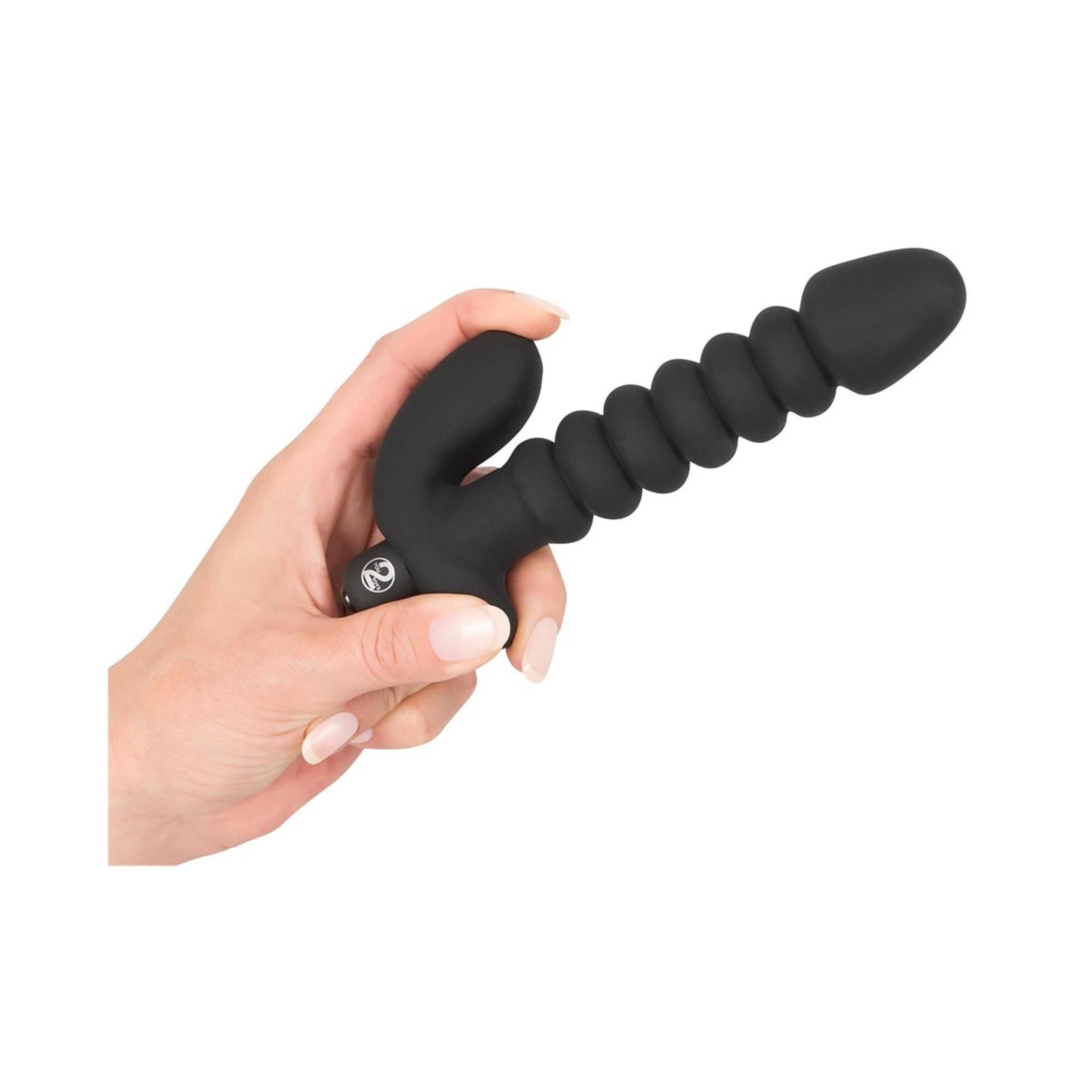 Hand hält schwarzen Vibrator mit Reizanker. Zylindrischer Schaft mit Rillen, gebogene Basis.