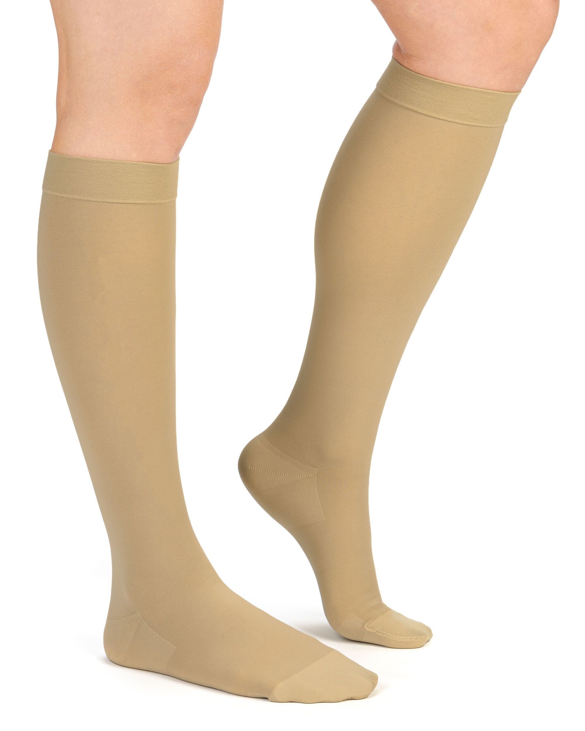 Beine mit Kompressionskniestrümpfen in Beige. Die Strümpfe reichen bis unter das Knie.